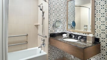 A bathroom with a bathtub, a sink with a mirror, and a shower.