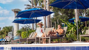 A poolside area with lounge chairs, umbrellas, and a water fountain.