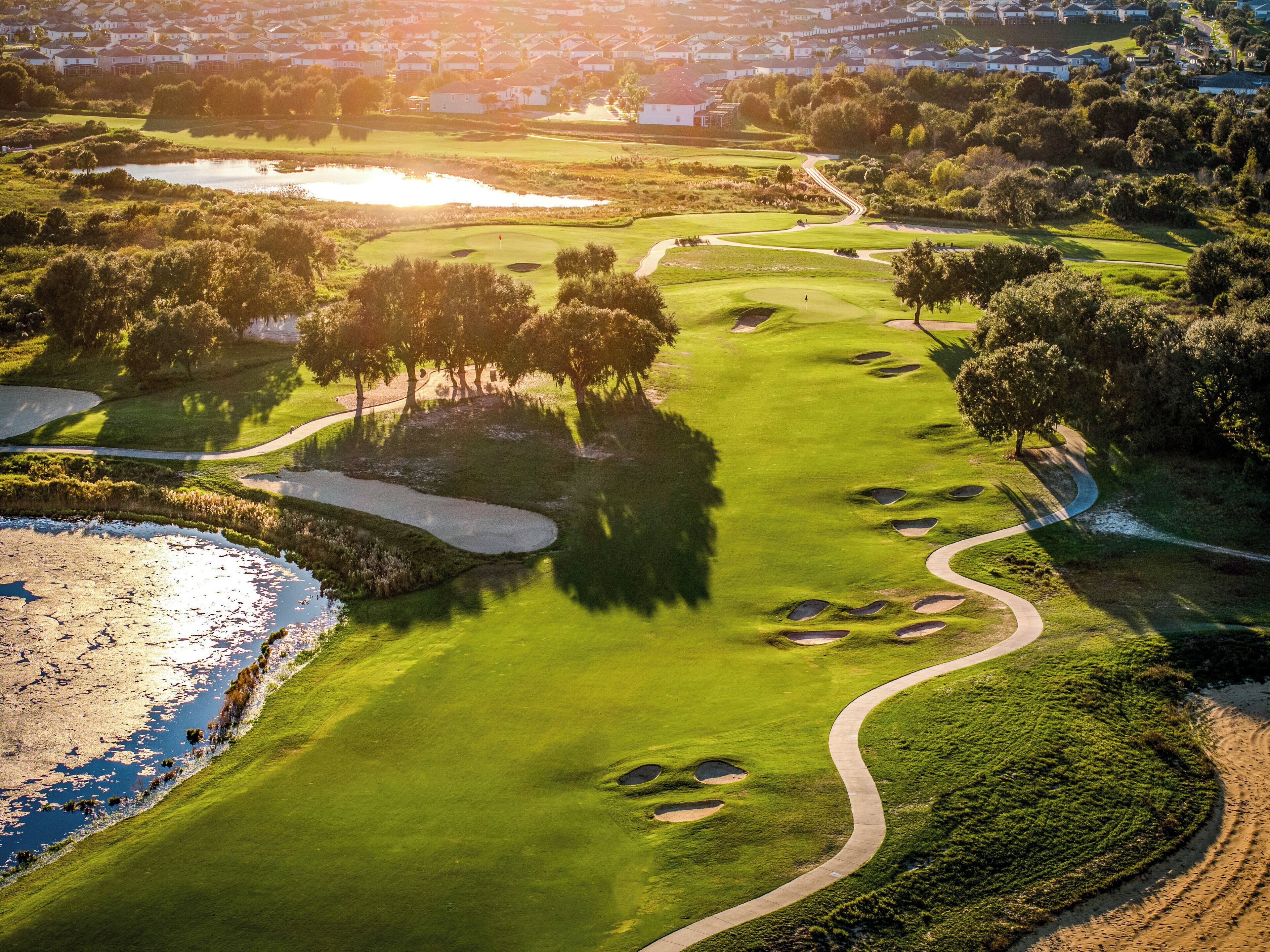 A golf course with bunkers, water hazards, and a winding path.