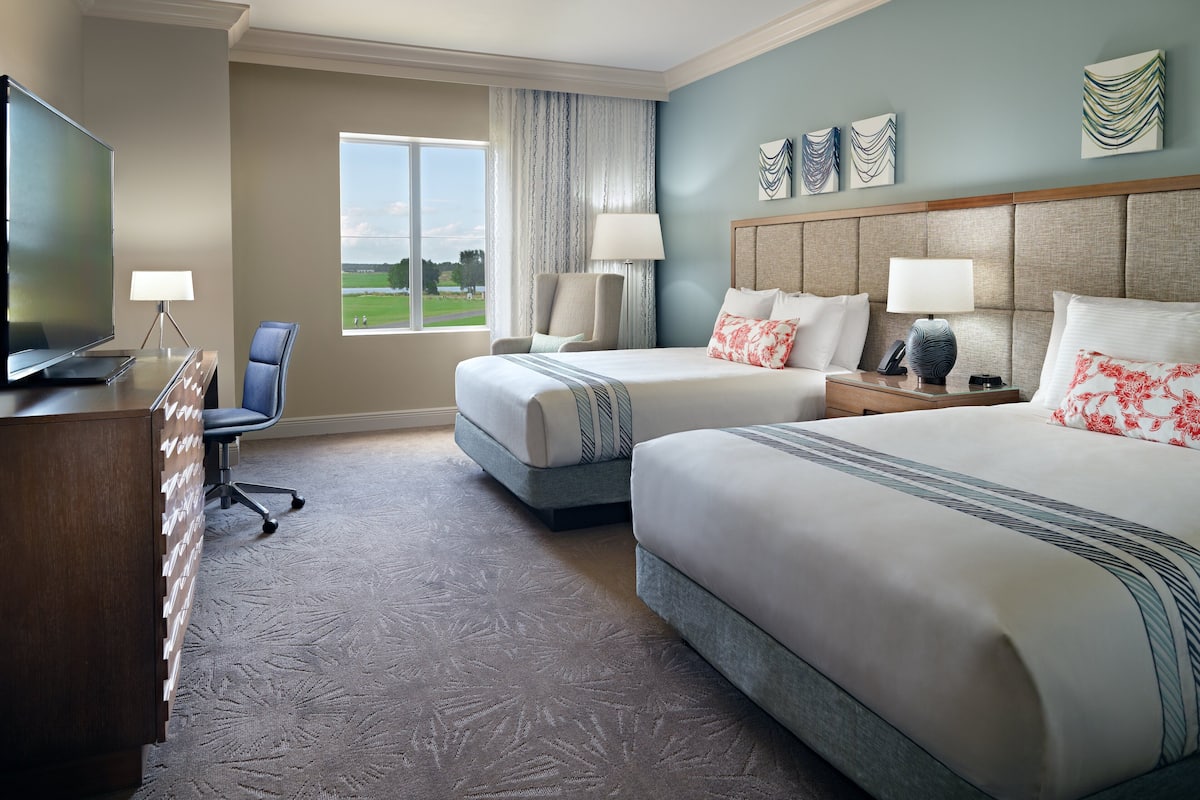 Une chambre d’hôtel avec deux lits, un bureau, une télévision et une vue sur l’extérieur.