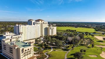 A large hotel with multiple buildings, a well-maintained golf course, and a clear blue sky.