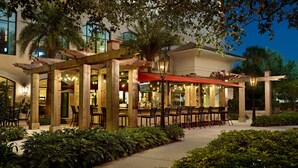 Un restaurant en plein air doté de pergolas, de tables et de chaises en bois, le tout entouré de verdure.