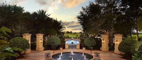 A courtyard with a central fountain, surrounded by potted plants and outdoor seating.