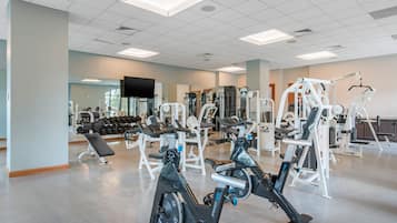 A gym with various exercise equipment, including treadmills, weight machines, and dumbbells.