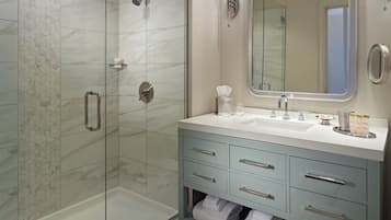 A modern bathroom with a glass-enclosed shower, a vanity with a sink, and a mirror.