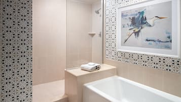 Ein modernes Badezimmer mit Badewanne, Dusche und einer Wand mit einem gerahmten Gemälde.