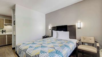A hotel room with a bed, a chair, a nightstand, and a wall-mounted TV.
