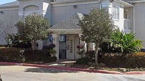 A two-story house with a front entrance, a satellite dish, and a garage. - Studio 6 Stafford, TX - Houston - Sugarland (Stafford)