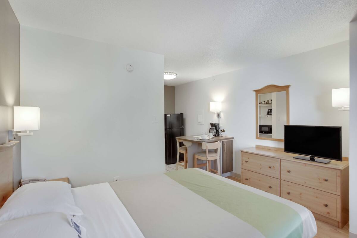 Une chambre d’hôtel comprenant un lit, un bureau avec une chaise, une télévision, une commode et un miroir.