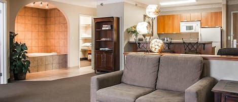 A living room with a sofa, a dining area with a table and chairs, a kitchen with appliances, and a bathroom with a shower and toilet.