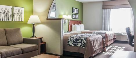 Habitación de hotel con sofá, dos camas, escritorio y lámpara.