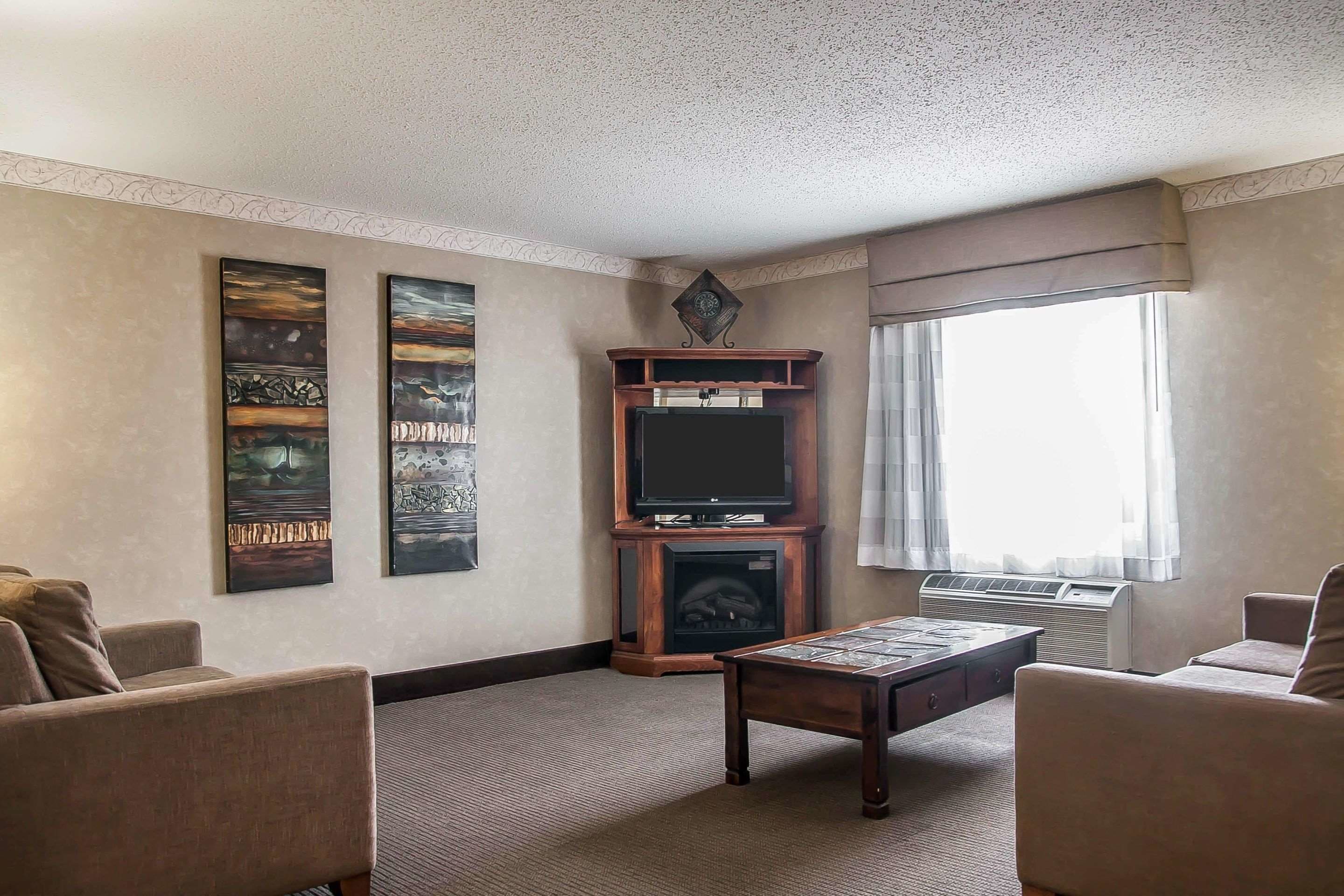Una sala de estar con chimenea, televisor y dos sillones.