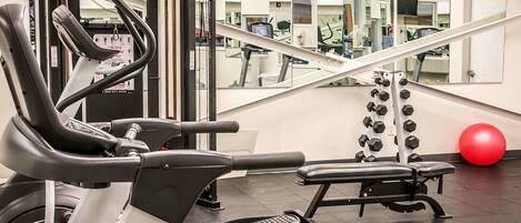 A gym with exercise equipment, including a treadmill, weight bench, and dumbbells.