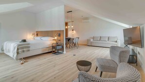 A modern hotel room with a large bed, a sofa, a TV, and a dining area. - Pestana Sintra Golf Conference & Spa Resort (Sintra)