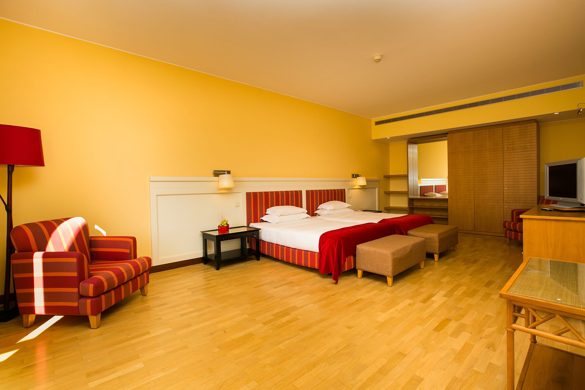 A hotel room with a bed, a desk, a chair, and a TV.