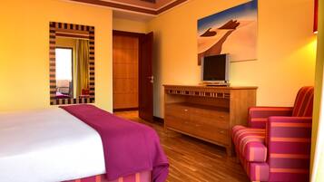 A hotel room with a bed, a wooden dresser, a TV, and a chair.