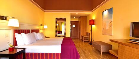 Une chambre d’hôtel avec un grand lit, des tables de chevet, un bureau, une chaise, une télévision et un miroir.
