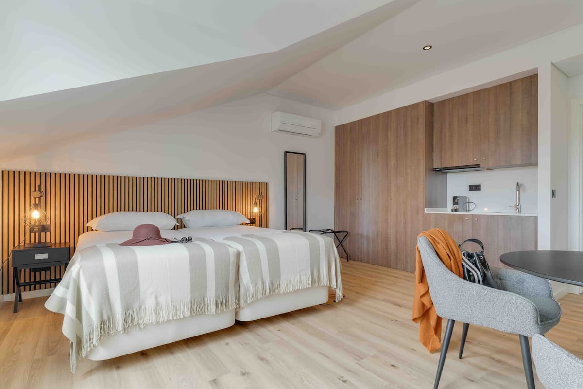 Quarto moderno com cama, mesa de cabeceira e um pequeno espaço de trabalho.