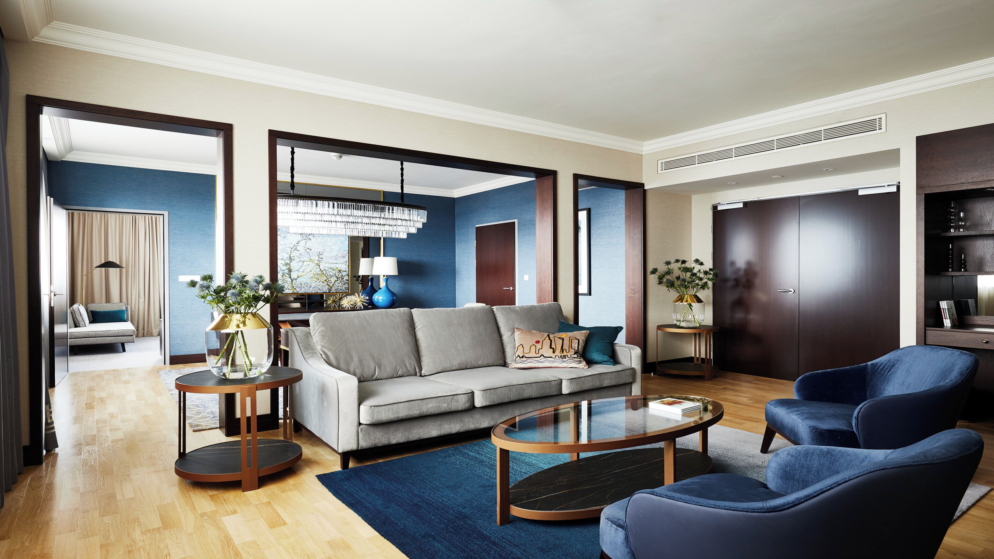Un salon moderne comprenant un canapé, des fauteuils, une table basse et une table d’appoint sur laquelle est posé un vase.