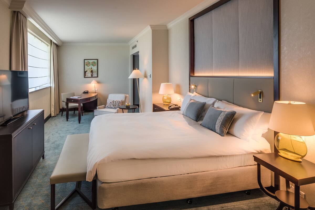 Una camera d'albergo con un letto grande, comodini, una scrivania, una sedia e un televisore.