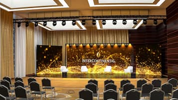A conference room with a stage, rows of chairs, and a backdrop with 'Intercontinental Warsaw' text.