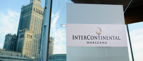 Señal del Hotel Intercontinental Warszawa, con una vista de un edificio histórico al fondo.
