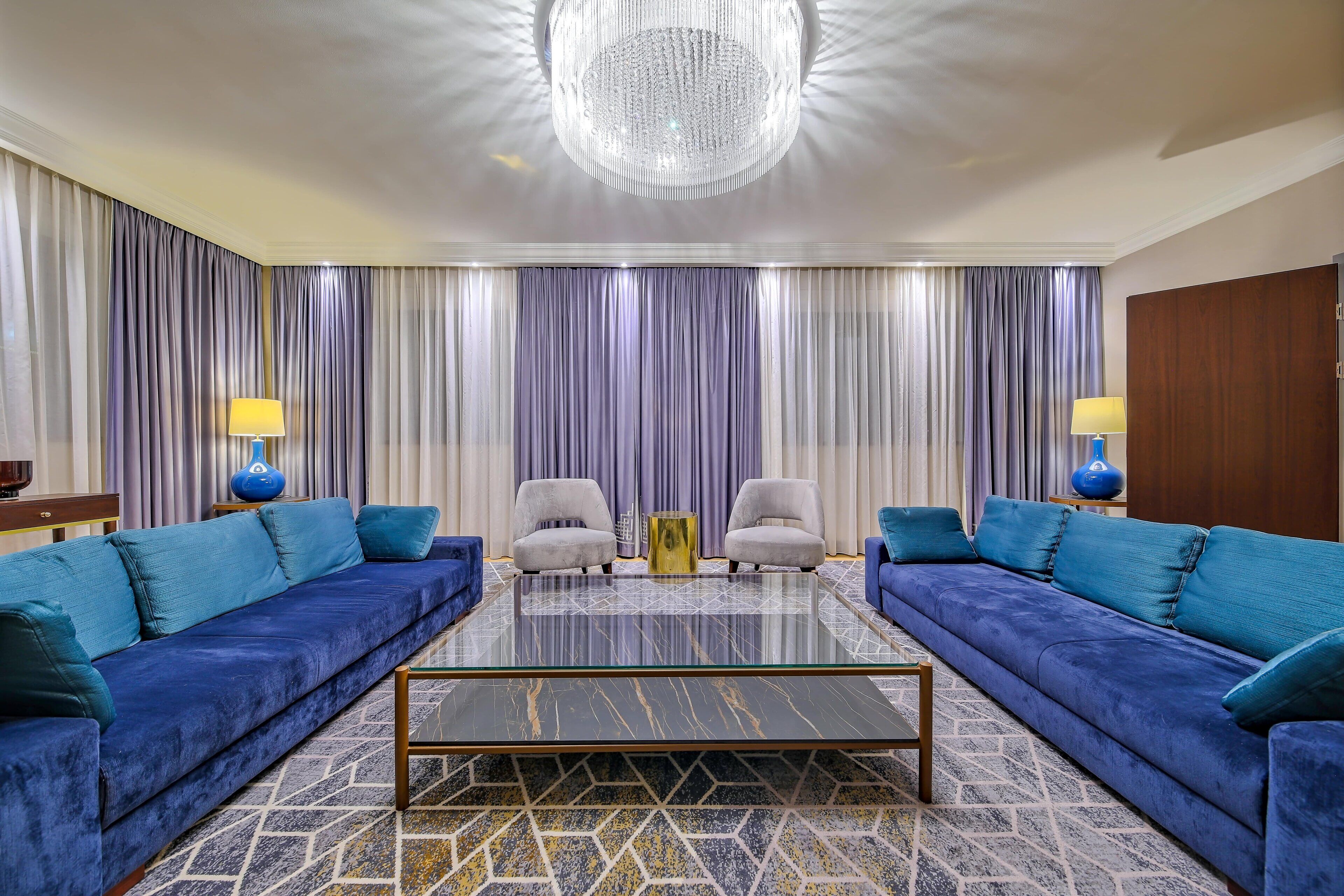 A modern living room with two sofas, a coffee table, and a chandelier.
