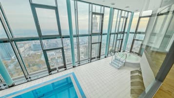 A high-rise building with a large indoor swimming pool and panoramic city views.