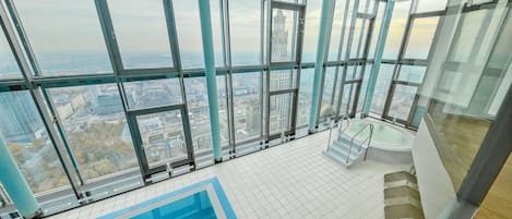 A high-rise building with a large indoor swimming pool and panoramic city views.
