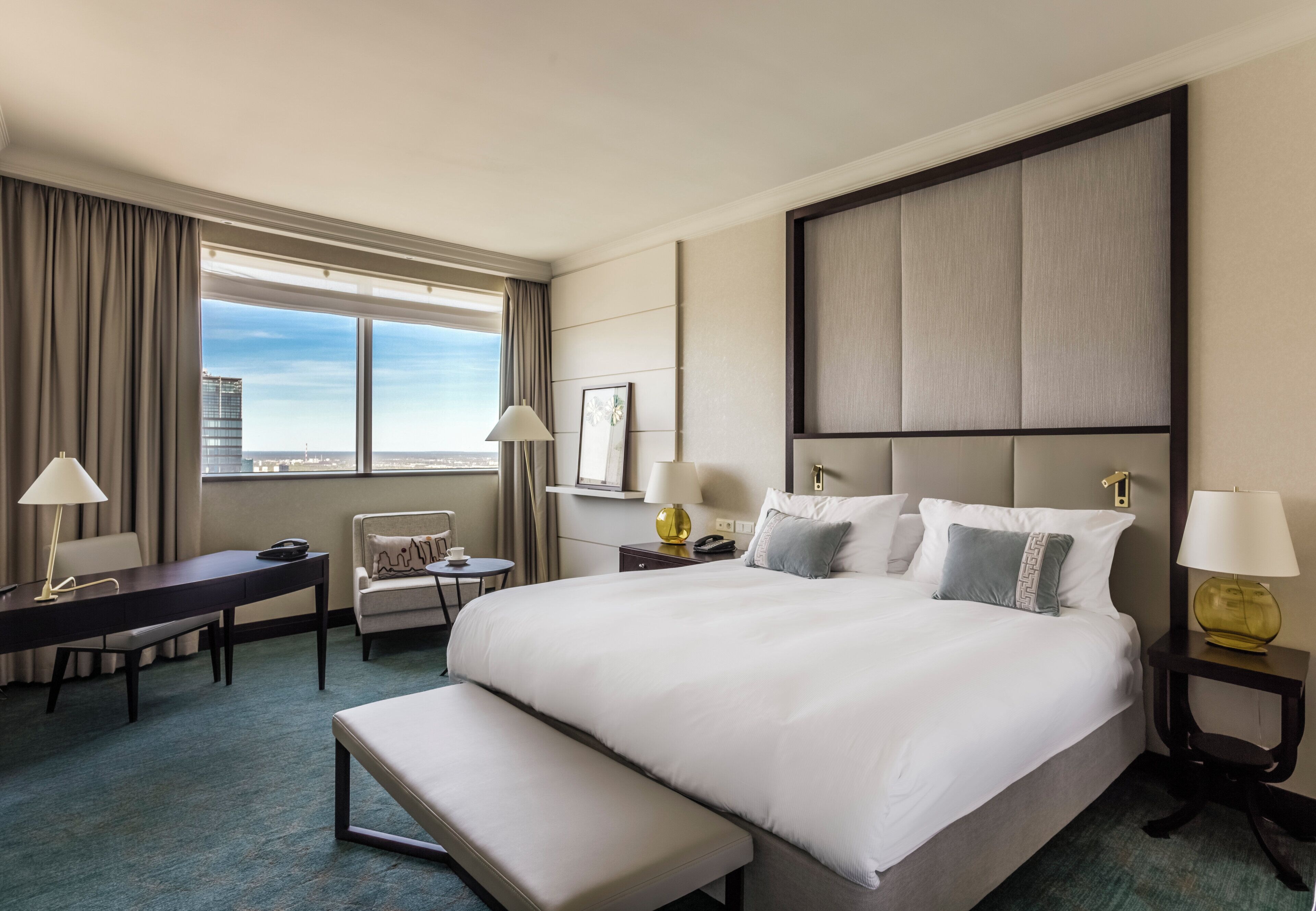 Hotelkamer met een groot bed, een bureau, een stoel en uitzicht op de stad.