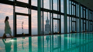 A large indoor swimming pool with a view of a clock tower through large windows. - InterContinental Warsaw by IHG (Warsaw)