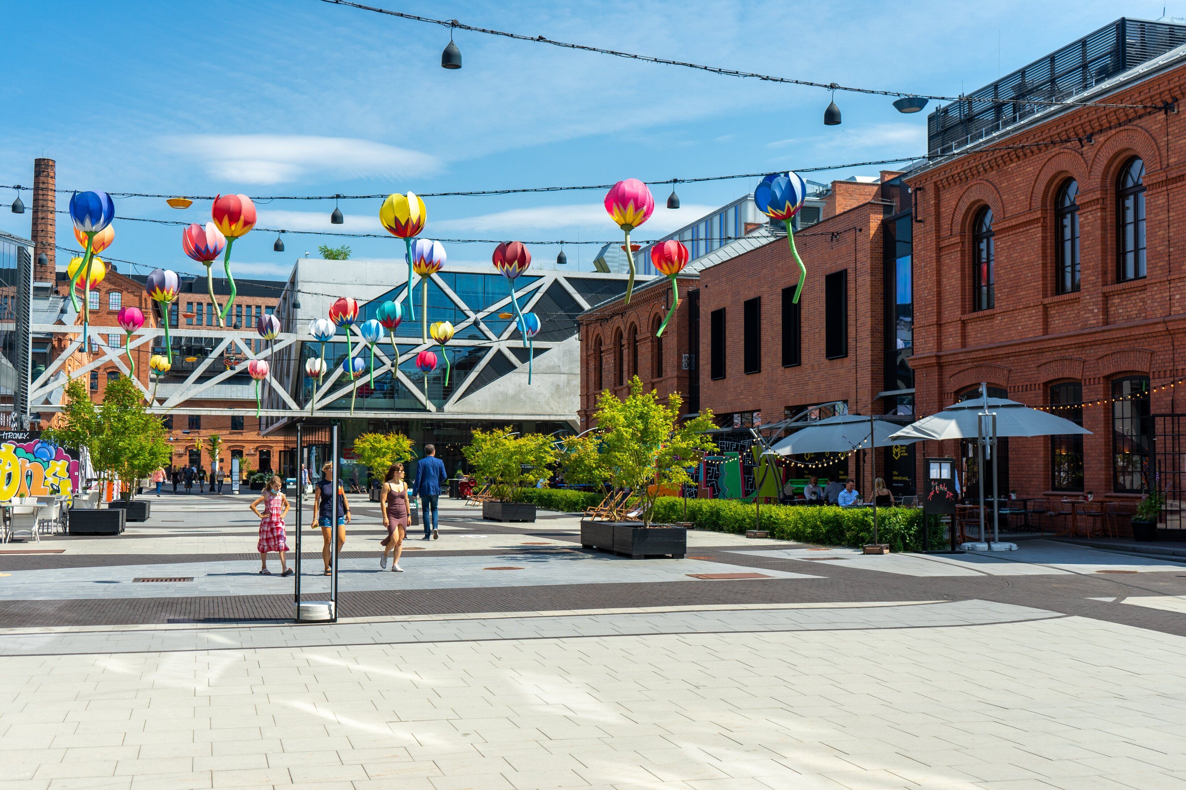 A public square with a modern building, outdoor seating, and decorative elements.