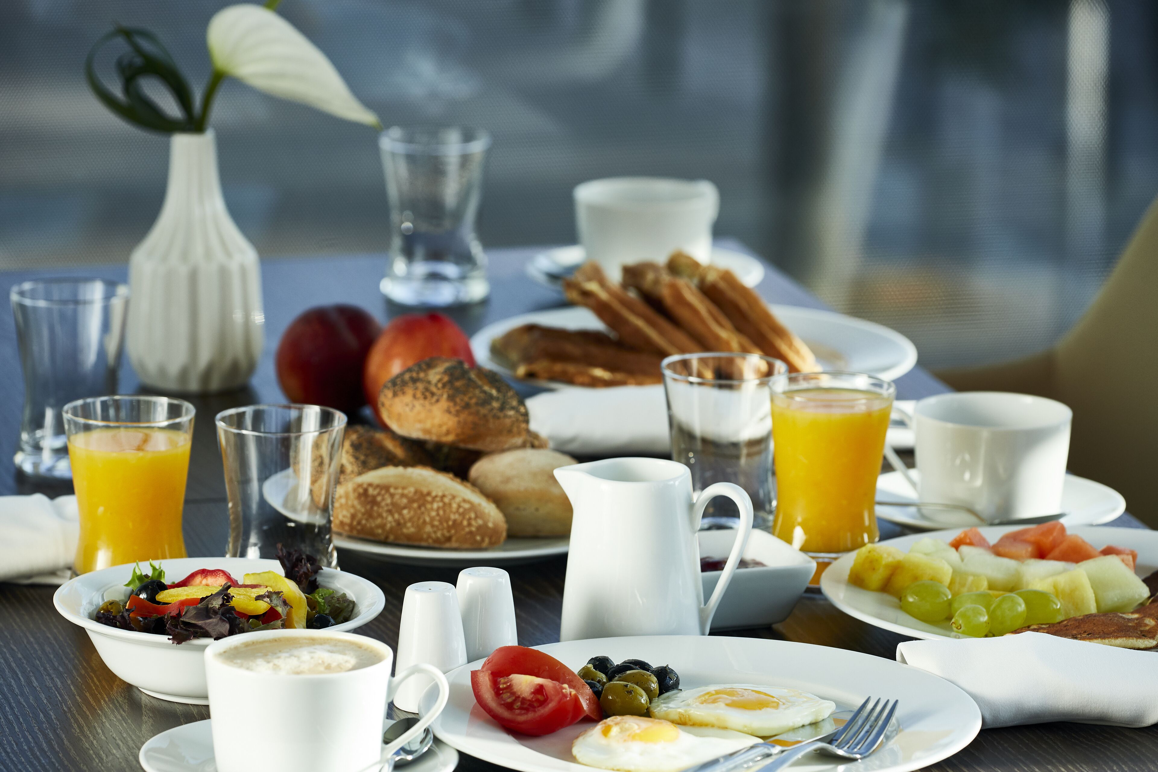Una tavola imbandita per la colazione, con diverse pietanze tra cui uova, pane tostato e frutta.