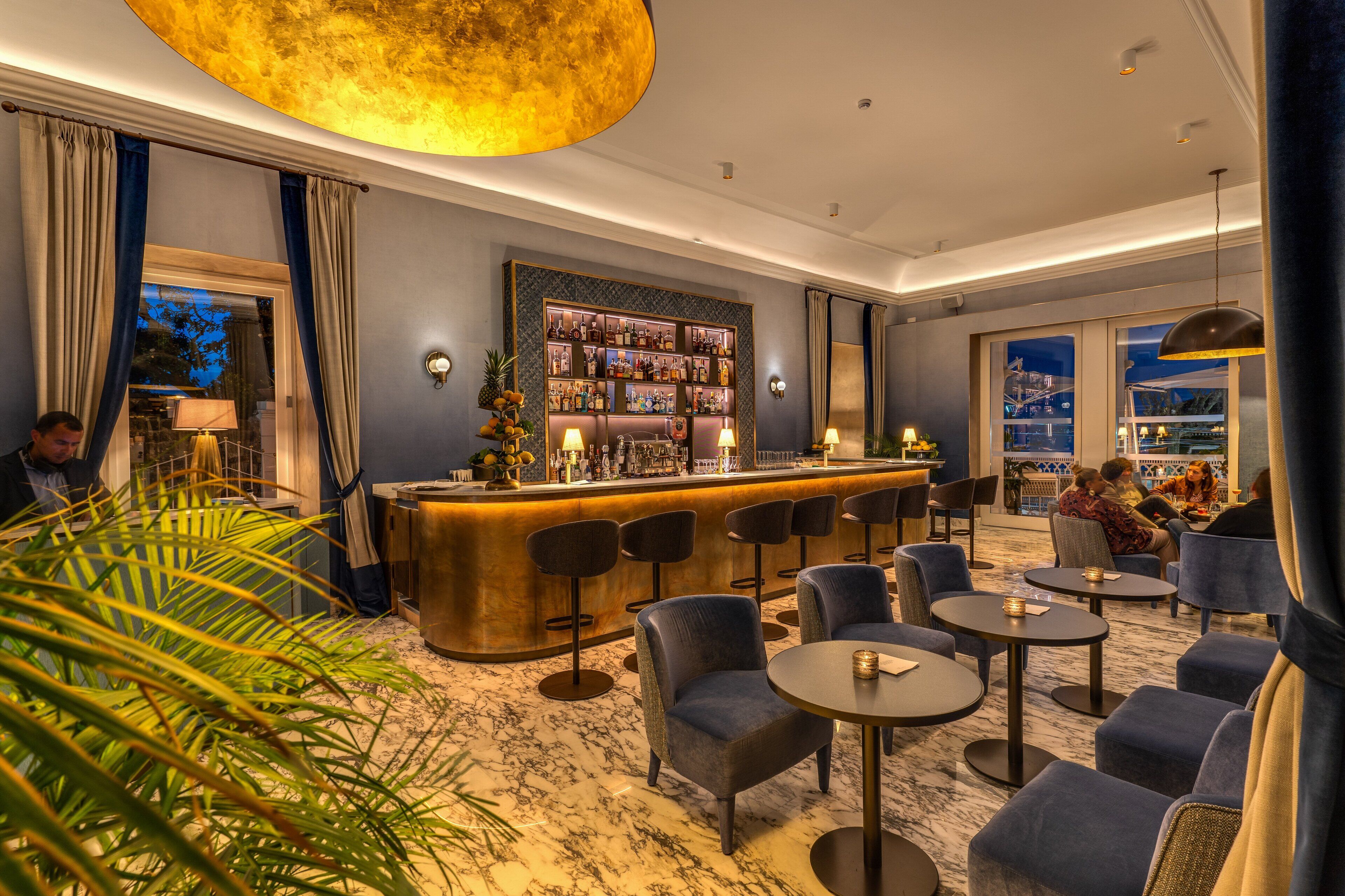 A bar area with a marble floor, bar stools, and a well-lit bar counter.