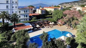 A hotel with a swimming pool, outdoor seating, and a view of a mountain.