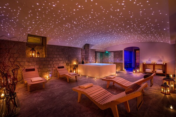 Una spa con lettini in legno, una vasca idromassaggio e illuminazione d'atmosfera.