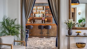 A bar area with a marble floor, bar stools, and a well-stocked liquor shelf. - Hotel Mediterraneo (Sant'Agnello)