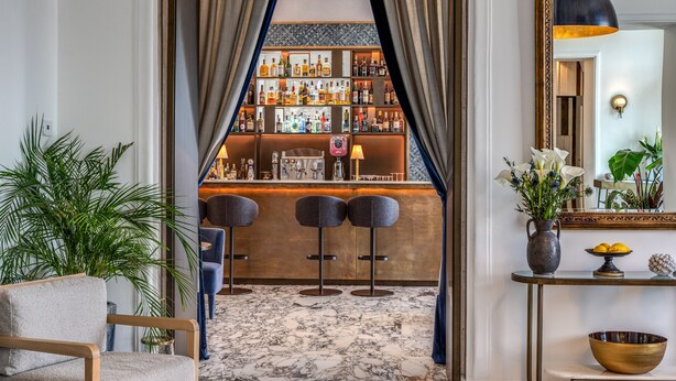 A bar area with a marble floor, bar stools, and a well-stocked liquor shelf. - Hotel Mediterraneo (Sant'Agnello)
