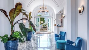 A spacious lobby with marble flooring, blue armchairs, and large potted plants. - Hotel Mediterraneo (Sant'Agnello)