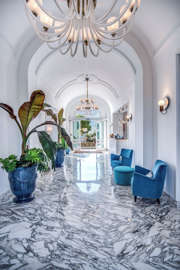 A spacious lobby with marble flooring, blue armchairs, and large potted plants. - Hotel Mediterraneo (Sant'Agnello)