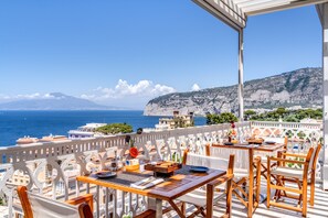 Enjoy a meal with a view of the sea and surrounding mountains from this outdoor dining area.