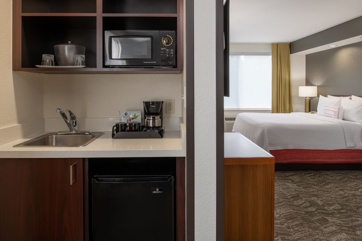 A compact hotel room with a kitchenette, including a microwave, coffee maker, and sink.
