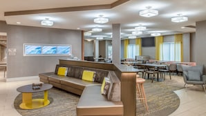 A modern hotel lobby with a sectional sofa, a round table, and a bar area. - SpringHill Suites by Marriott Portland Airport (Portland)