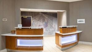 A reception area with two counters, a wall with text, and a sign for the business center. - SpringHill Suites by Marriott Portland Airport (Portland)