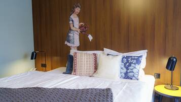 Ein ordentlich bezogenes Bett mit einer gemusterten Decke, einem Holz-Kopfteil und einer Wandlampe.