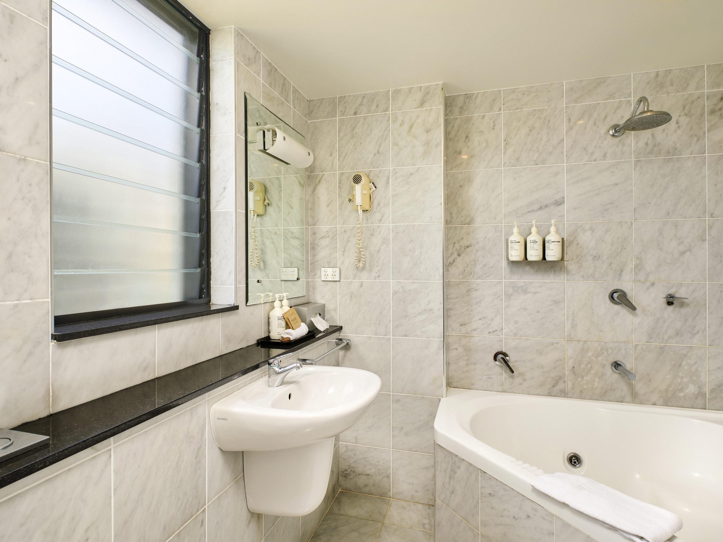 A bathroom with a sink, mirror, and bathtub.
