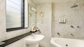 A bathroom with a sink, mirror, and bathtub.