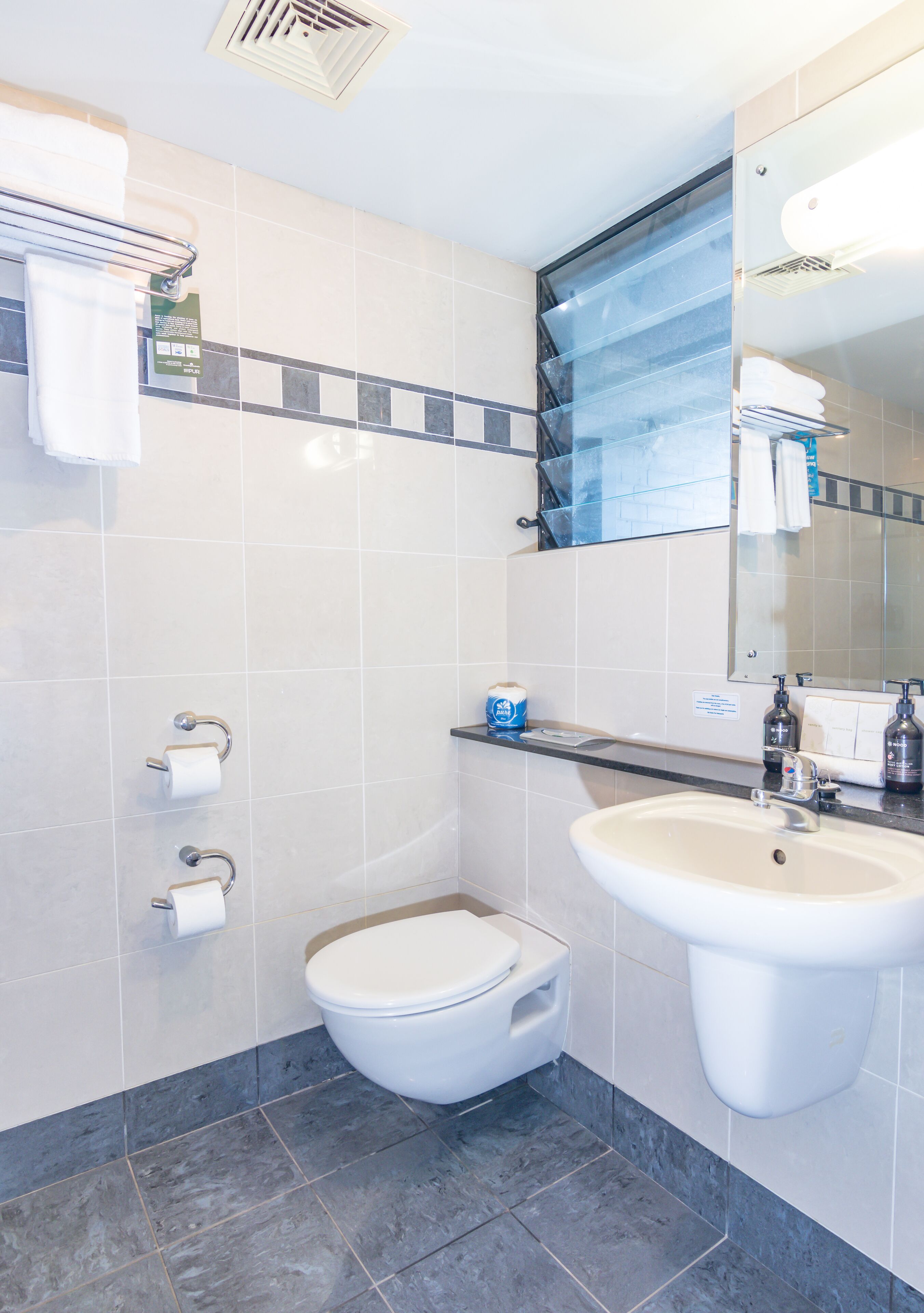 A modern bathroom with a toilet, sink, and towel rack.