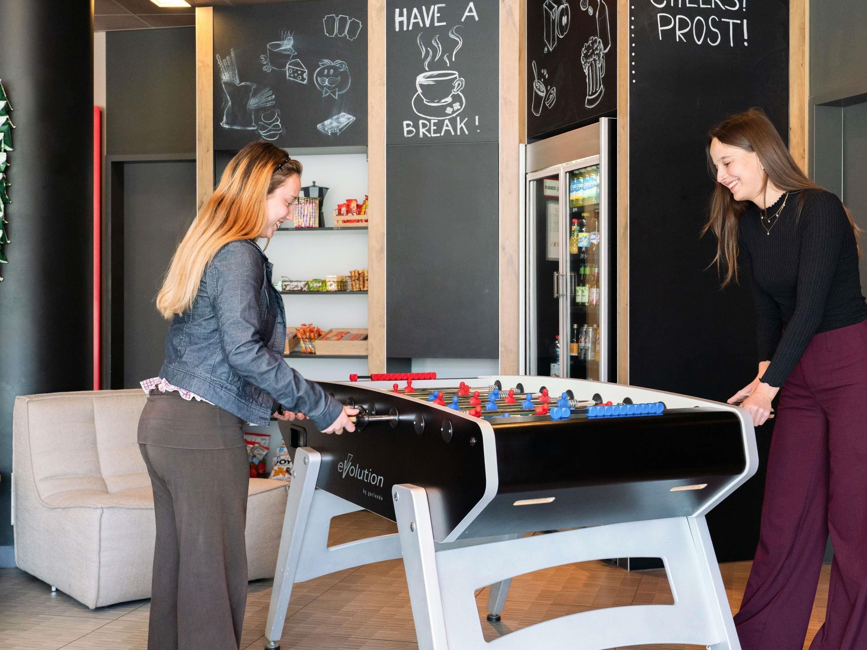 Une table de baby-foot dans une pièce aux murs noirs, décorée d’œuvres d’art réalisées à la craie.