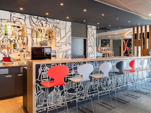 A bar area with a counter, stools, and a wall with abstract designs. - ibis Bern Expo (Bern)
